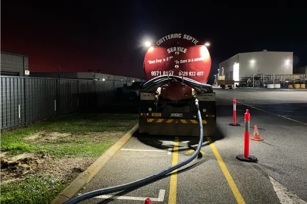Chittering Septic Service tanker pumping out a grease trap at a commercial site at night