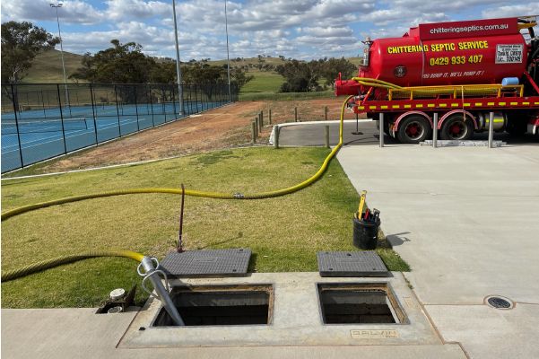 Tanker pumping out open pits beside tennis courts at a sports facility
